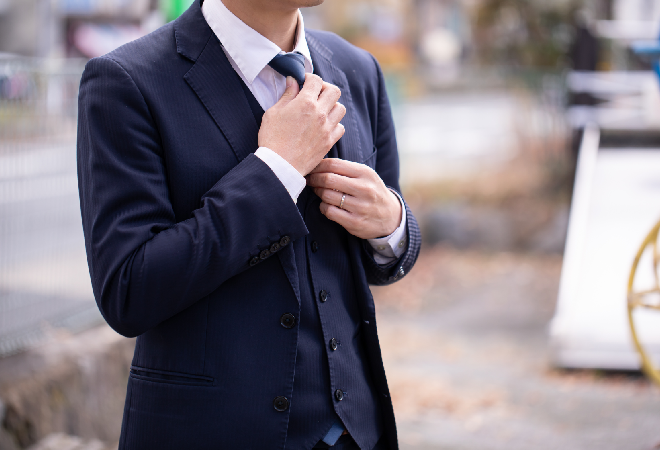 ネクタイを整えるスーツ姿の男性。