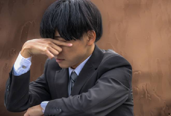 悩み苦しむスーツの男性。